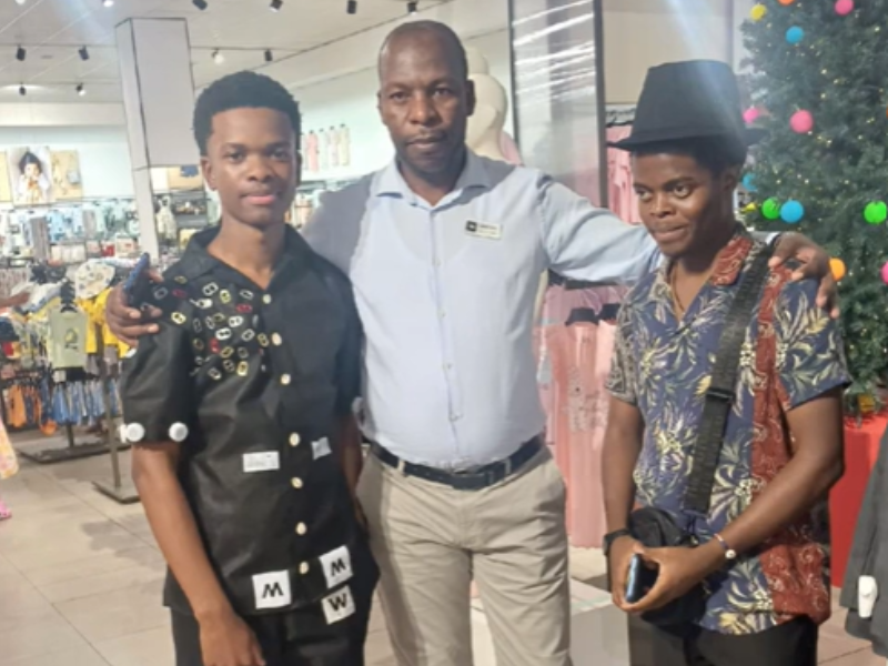 A young man dressed in a Woolworths shopping bag ensemble with two other people