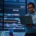 A young multiethnic man using a laptop to monitor computer systems