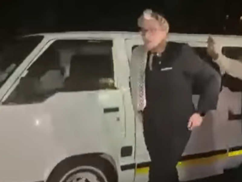 A young white caucasian boy exits a taxi wearing traditional zulu headgear