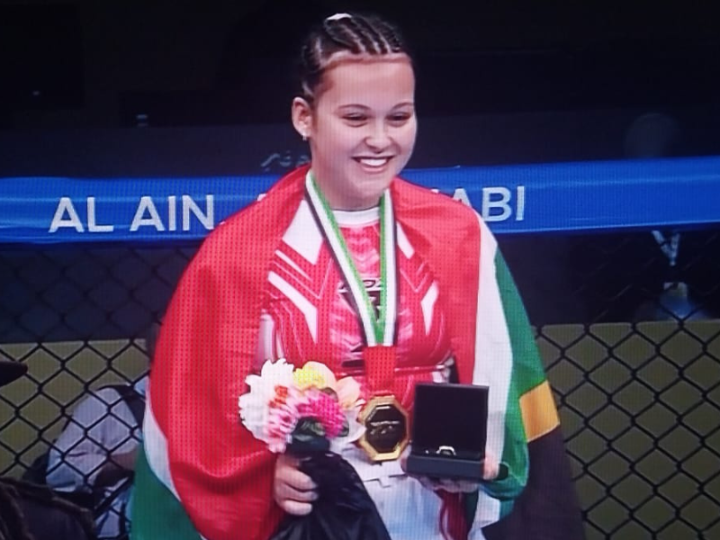 Abigail Deneys standing on the podium with her gold medal in Abu Dhabi