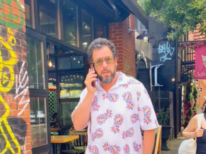 Adam Sandler walking in New York on a phone call