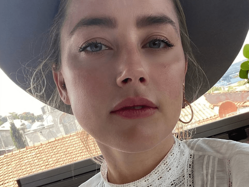 Amber Heard wearing a wide-brimmed hat and a white lace top