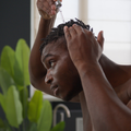 An African man applies oil to his hair using a dropper