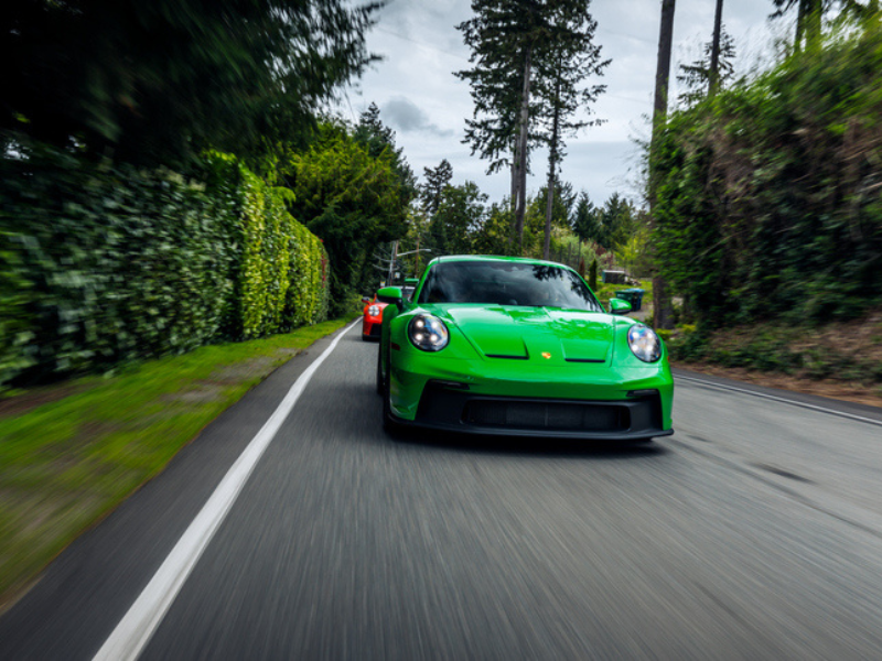 An Apple Green Porsche 911 speeding on the road