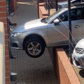 An Audi vehicle hangs off the side of a wall over the parking bay