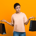 An Indian woman holds two shopping bags in her hands uncertain which one to choose