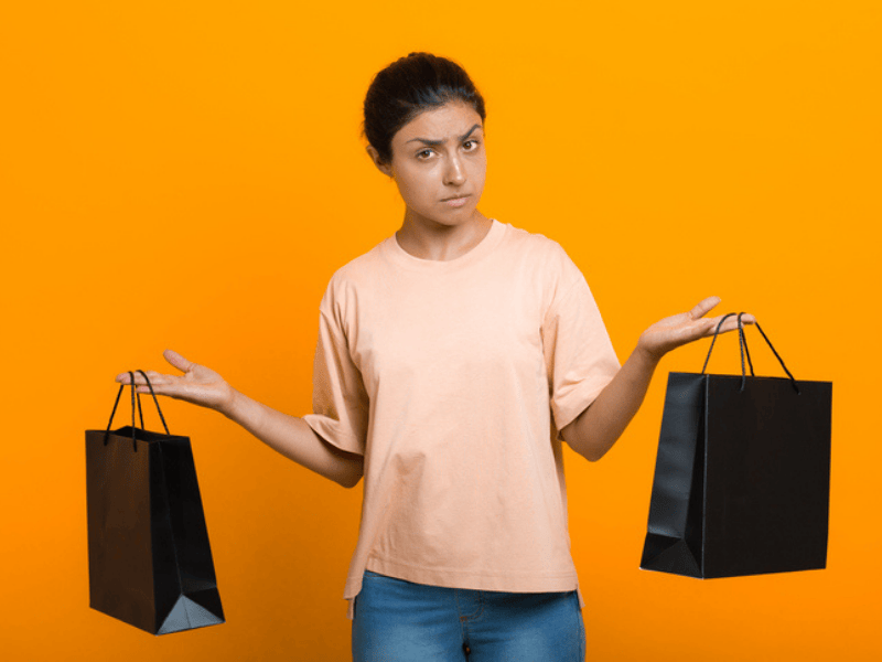 An Indian woman holds two shopping bags in her hands uncertain which one to choose