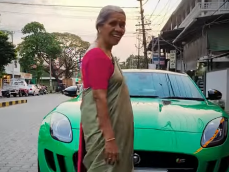 An Indian woman stands in front of a green Jaguar sports car