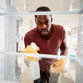 An adult man cleaning inside a refridgerator