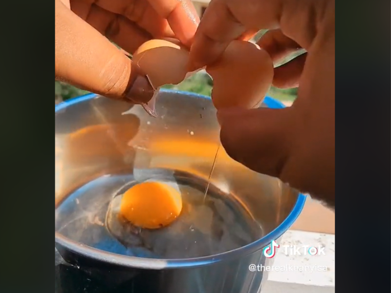 An egg frying in a pot outside