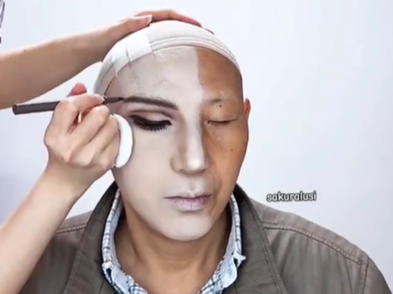 An elderly man gets his makeup done
