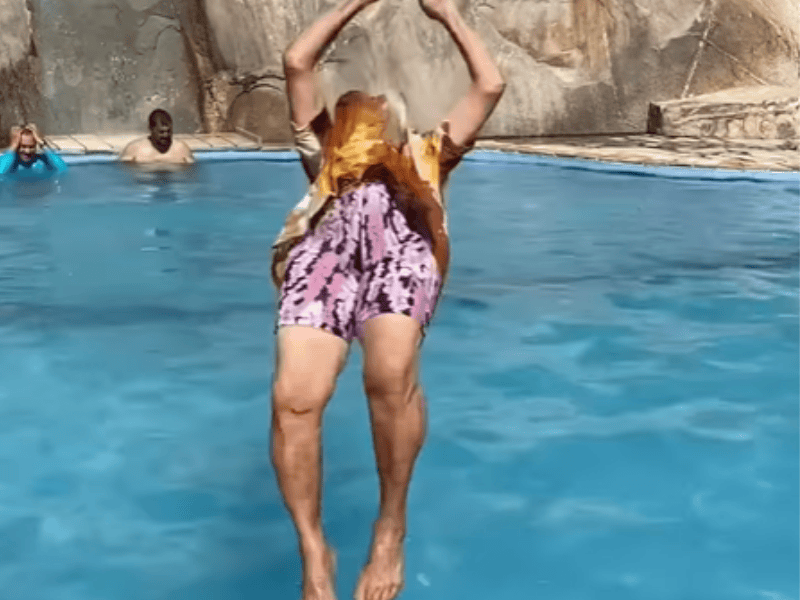 An elderly woman somersaults into the pool