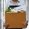 An employee holds a box with their belongings and a resignation letter