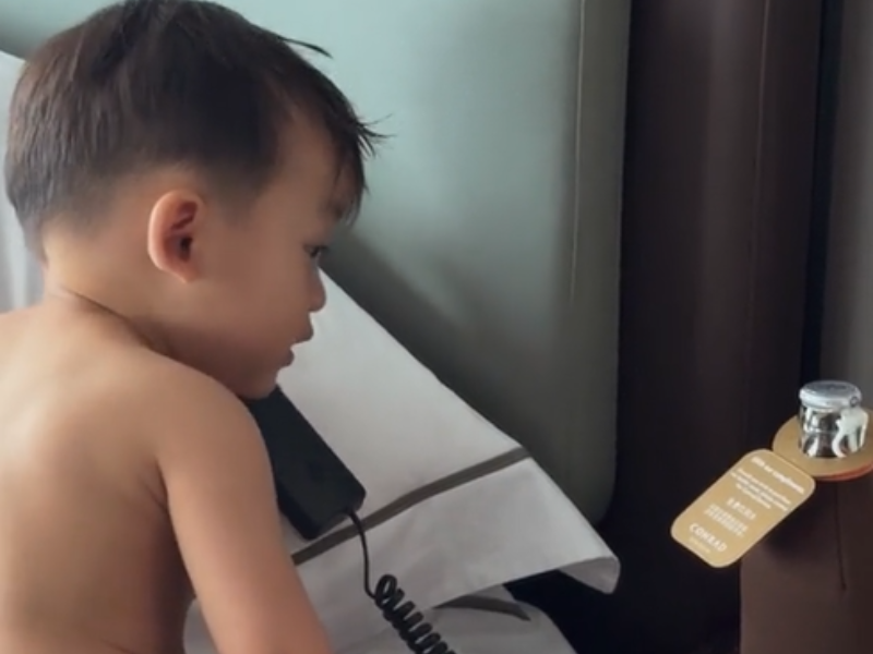 An infant talking on the phone inside a hotel room