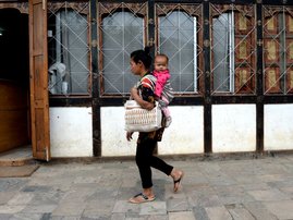 a Bhutanese woman carries her child on a saddle on the streets of Thimphu in Bhutan.