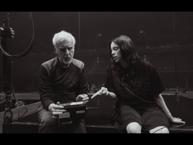 Titanic director James Cameron and Billie Eilish sitting on a stage