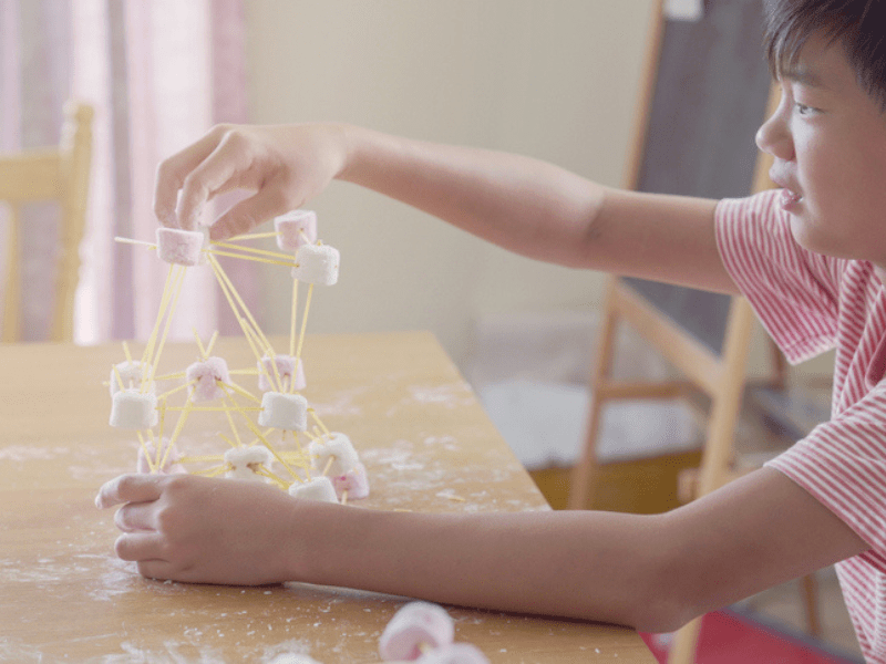 Boy builds a tower with spaghetti and marshmallows