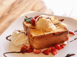 Thick slice of toast with ice cream strawberries and chocolate sauce