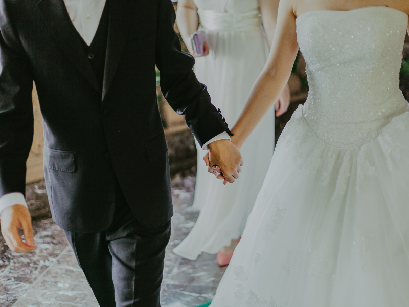 Bride and groom holding hands with woman in background
