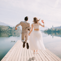 Bride and groom jump for joy on a wooden pier