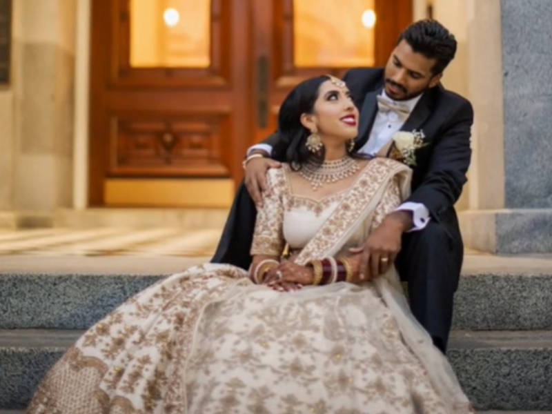 Bride looks at groom while both are seated on a staircase