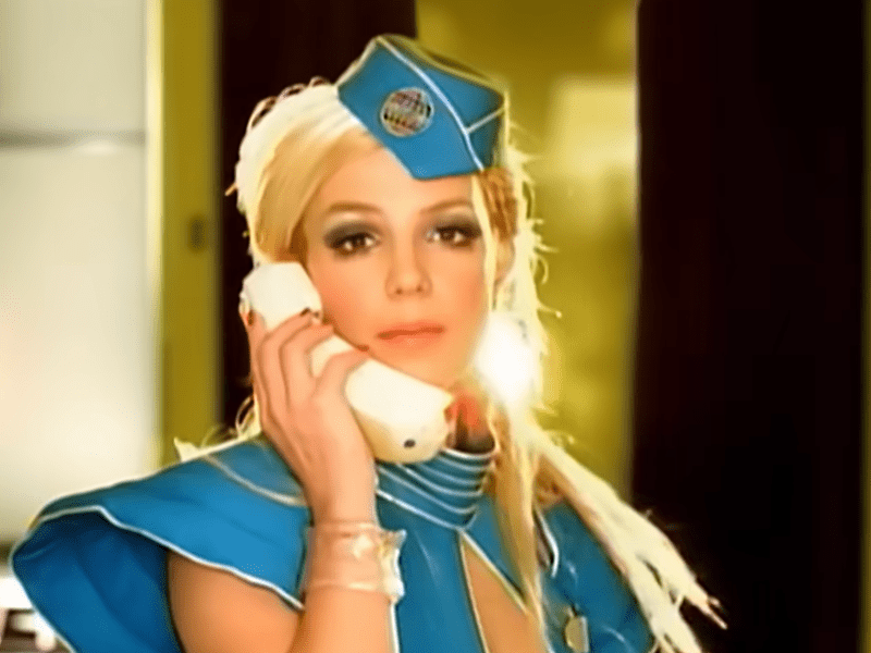 Britney Spears wearing a bright turquoise flight attendant uniform
