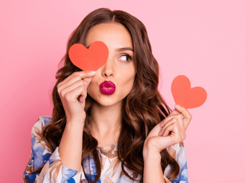 Brunette woman holding to red paper hearts