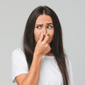 Brunette woman holds her nose due to odour smell