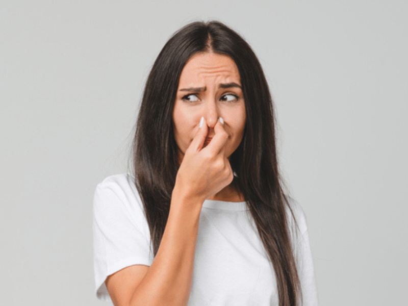 Brunette woman holds her nose due to odour smell