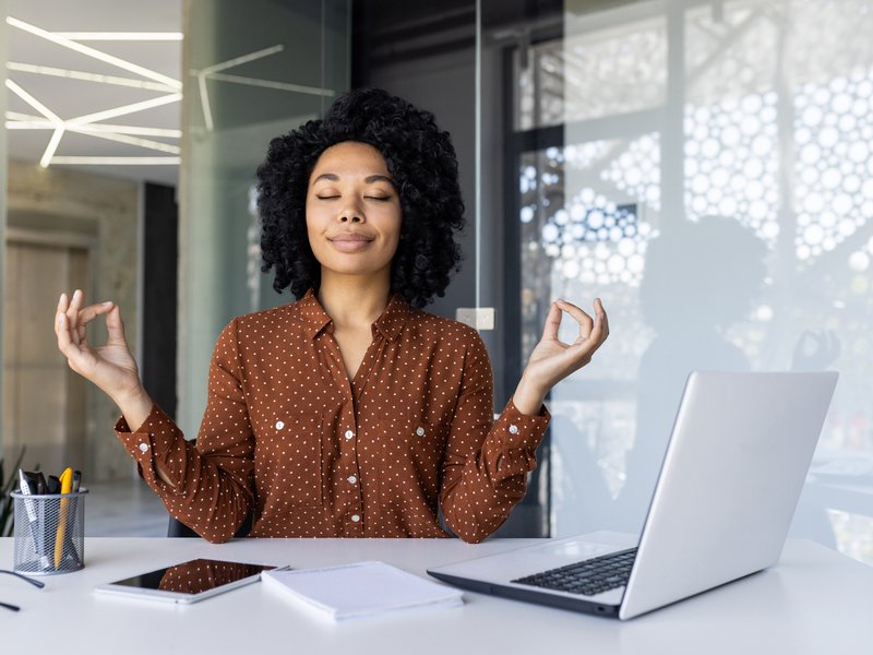 Businesswoman practicing meditation at her office desk
