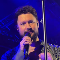 Calum Scott looks at a praying mantis on his mic stand