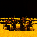 Four string players perform while surrounded by thousands of candles