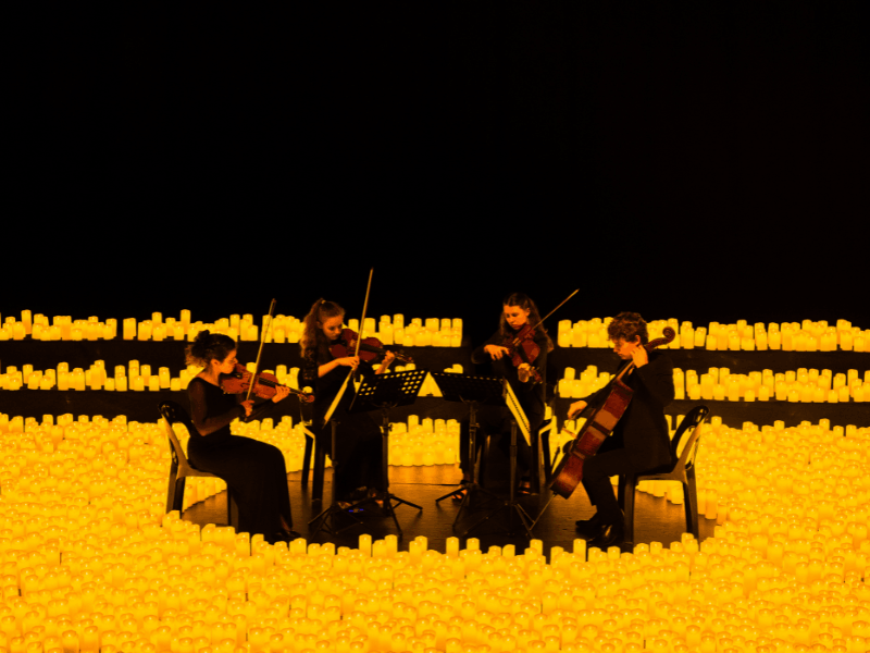 Four string players perform while surrounded by thousands of candles