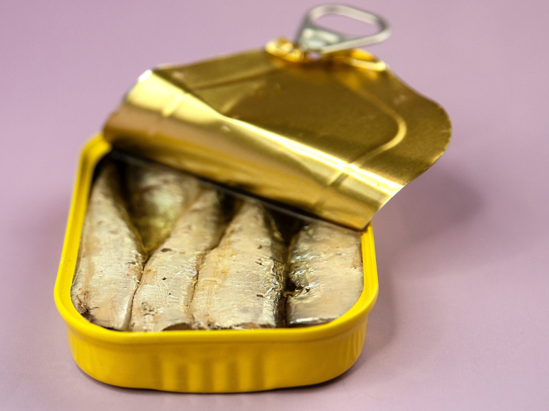 Canned fish in package on lilac background