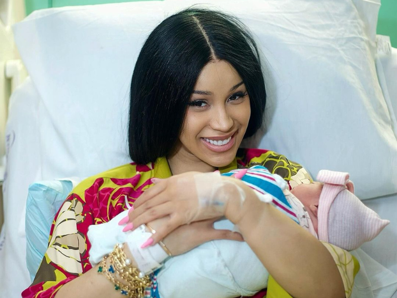 Cardi B sitting in a hospital bed while holding her newborn baby.png