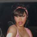 Cardi B wearing a pink dress in the backseat of a car