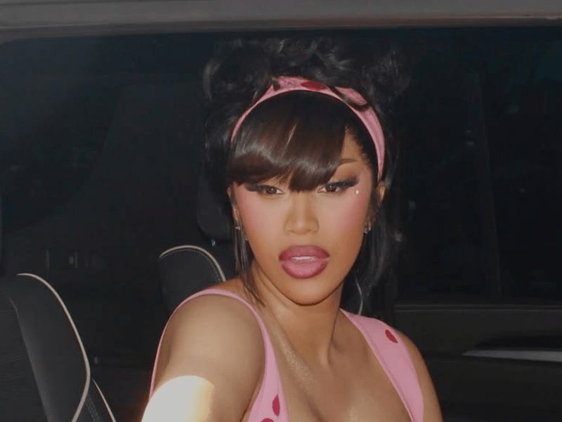 Cardi B wearing a pink dress in the backseat of a car