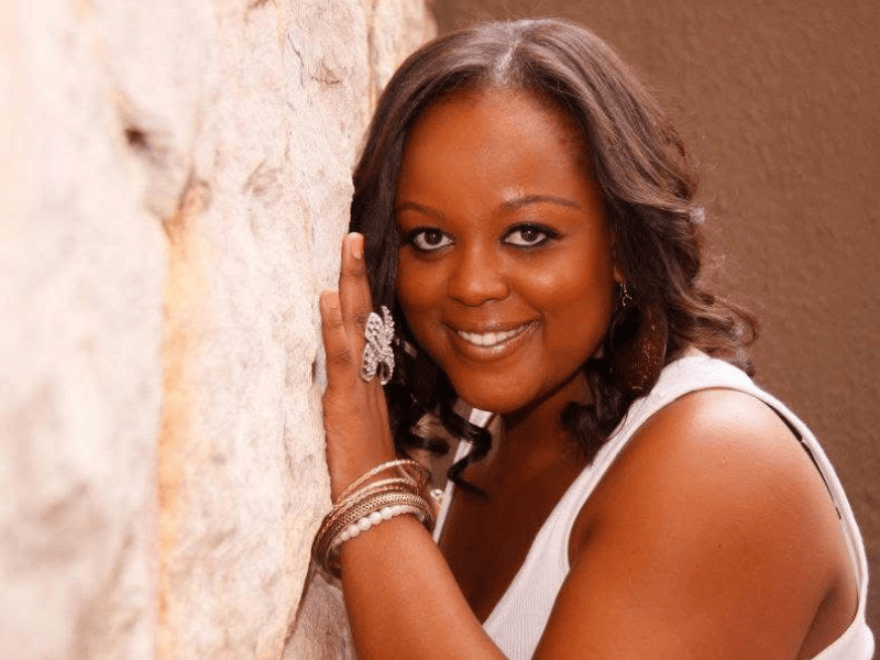 Carol Ofori posing near a wall in her twenties