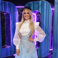 Carrie Underwood poses next to a neon lit Idols sign