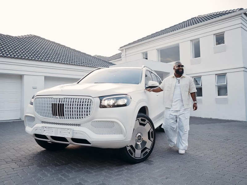 Cassper Nyovest poses next to a white Mercedes-Maybach GLS