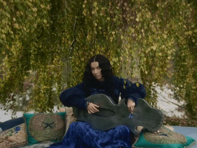Charli XCX plays a large string instrument
