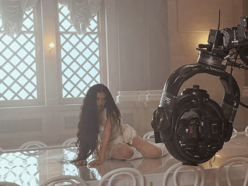 Charli xcx sitting on top of a large glossy table