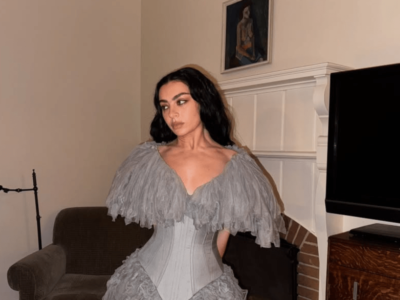 Charli XCX wears a grey high fashion dress