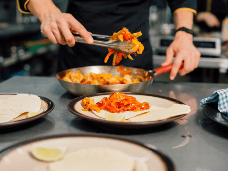 Chef preparing tacos on a steel table