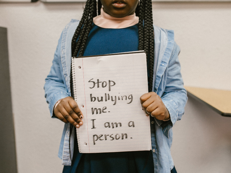 Child showing message written in a notebook about bullying