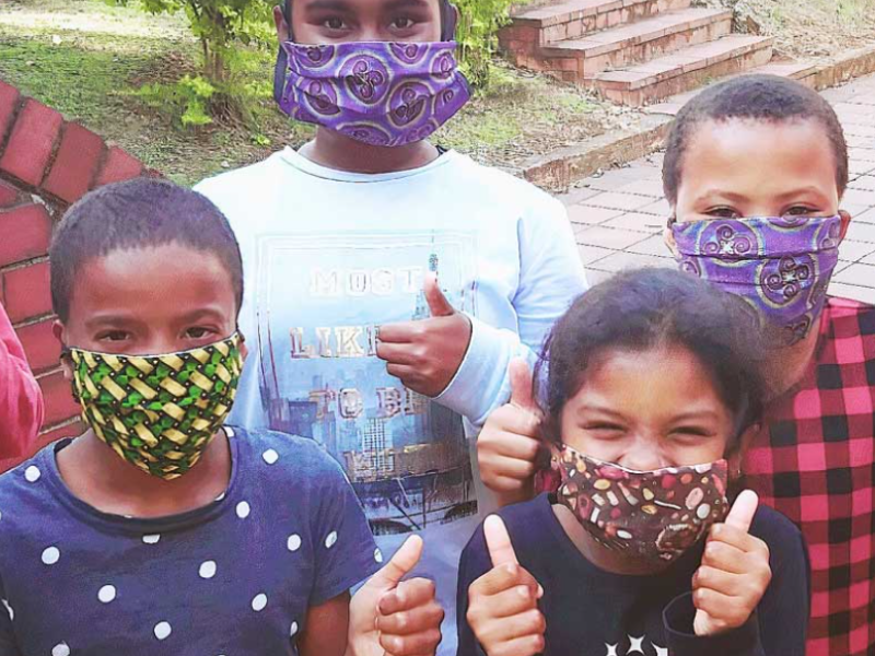 Children with their masks on and thumbs up