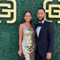 Chrissy Teigen and John Legend pose in front of a green backdrop