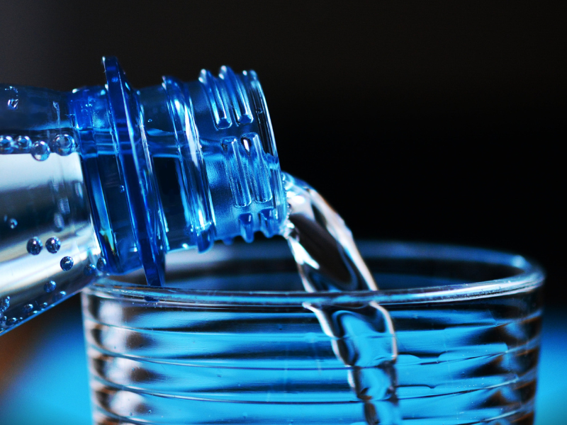 Close up of bottle pouring water into glass