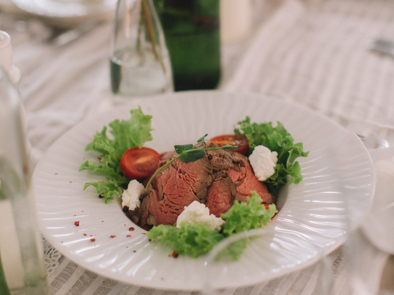 Cooked meat with vegetables on white plate at wedding