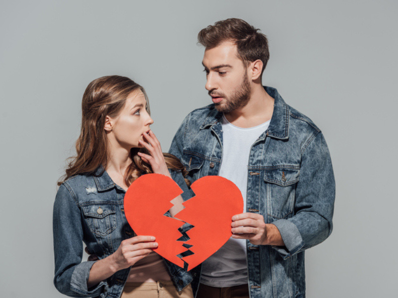 Couple holding pieces of a broken heart symbol